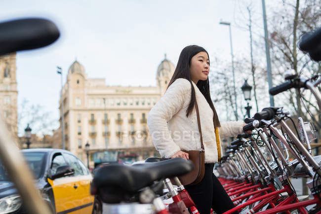 Young chinese woman renting a bicycle in Barcelona — Stock Photo