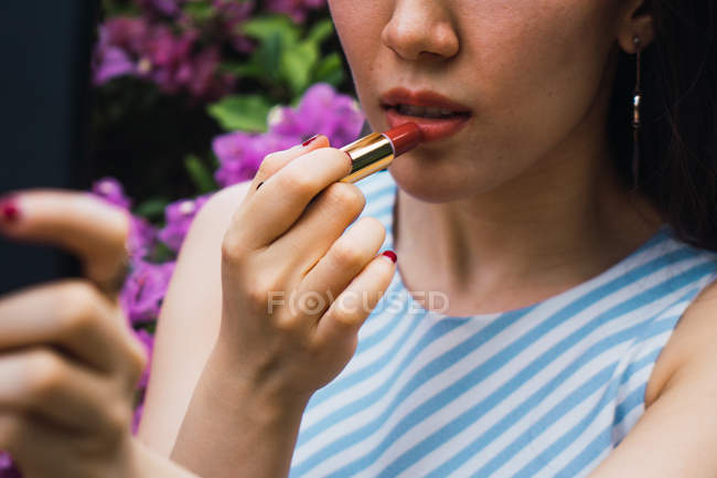 Junge asiatische Frau, die Lippenstift aufträgt — Stockfoto