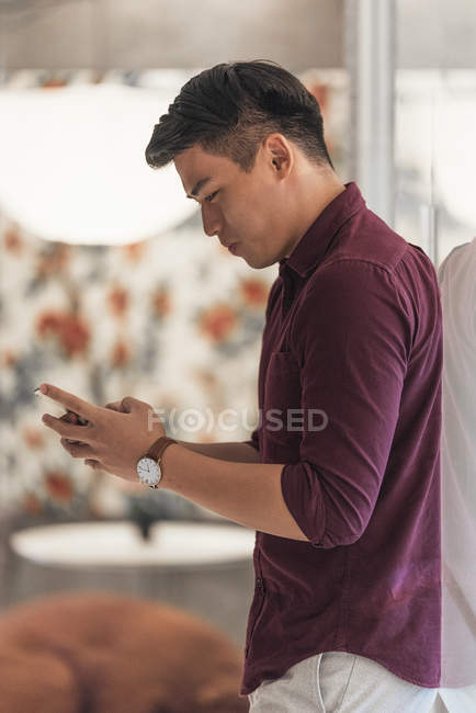 Jeune homme d'affaires asiatique en utilisant smartphone dans le bureau moderne — Photo de stock