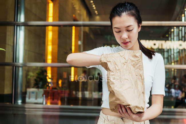 Joven atractivo asiático mujer con papel bolsa - foto de stock
