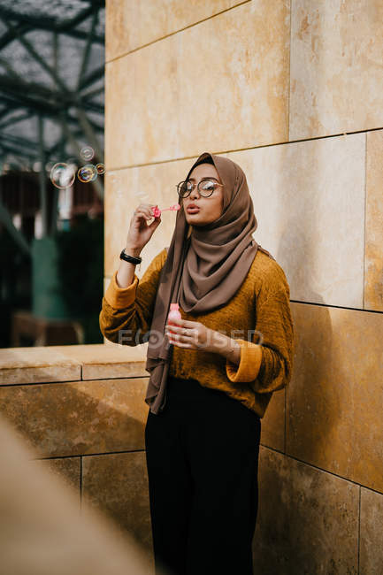 Jeune asiatique musulman femme dans hijab fabrication bulles à rue — Photo de stock