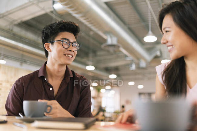 Jóvenes asiático empresarios hablando en moderno oficina - foto de stock