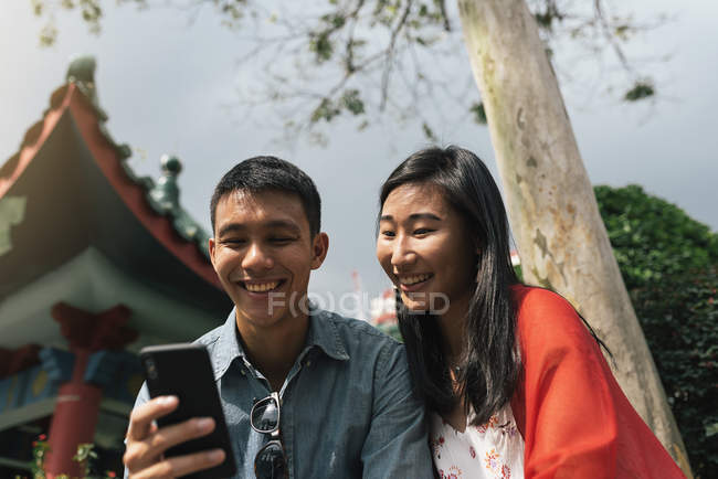 Молода азіатська пара проводить час разом у місті та використовує смартфон — стокове фото