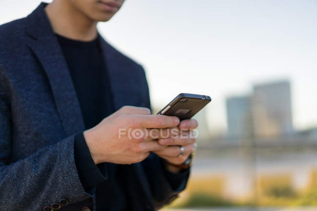 Imagen recortada de hombre joven utilizando el teléfono inteligente - foto de stock