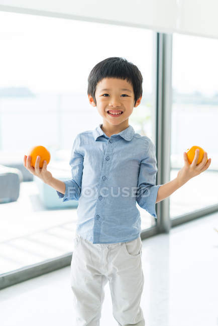 Lindo poco asiático chico holding naranja frutas - foto de stock