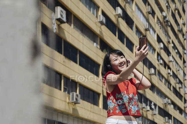 Asiático turista mulher tomando selfie contra casa — Fotografia de Stock