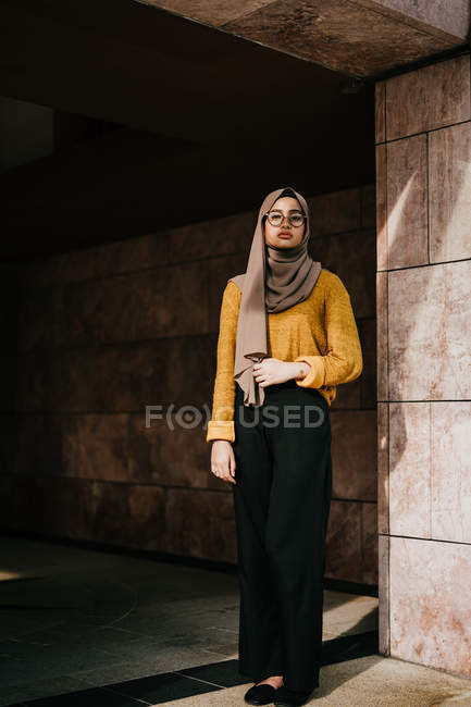 Joven asiático musulmán mujer en hijab posando en edificio - foto de stock