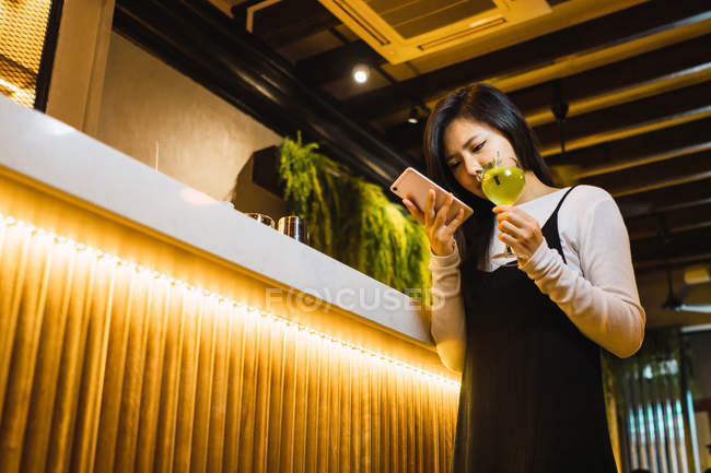 Jovem asiático mulher com inteligente e bebida no confortável bar — Fotografia de Stock