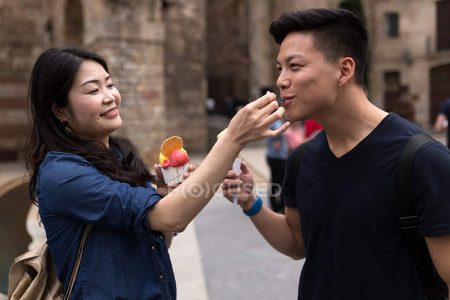 Retrato de una joven pareja de turistas comiendo helado en la calle . - foto de stock