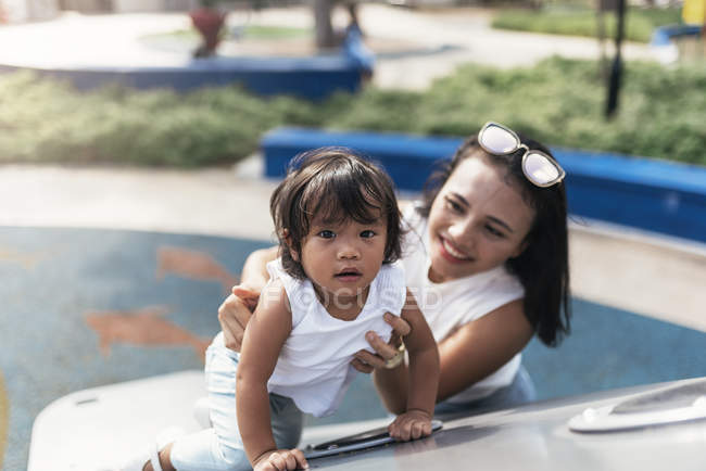 Junge Mutter mit asiatischer Tochter verbringt Zeit auf Spielplatz — Stockfoto