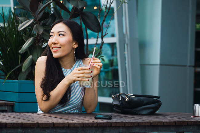 Young asian woman having drink in cafe — Stock Photo