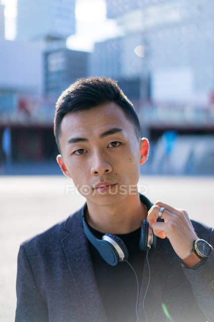 Jeune asiatique homme avec casque regardant caméra — Photo de stock