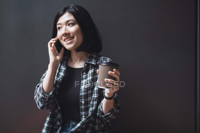 Young beautiful asian girl in casual clothes using smartphone on city streets — Stock Photo