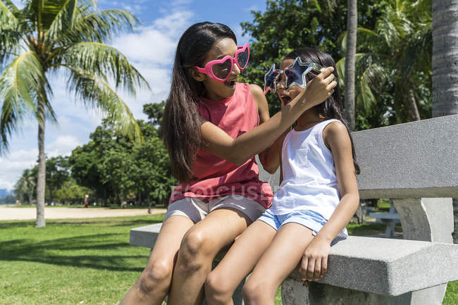 Madre e figlia indossano occhiali divertenti sulla panchina — Foto stock