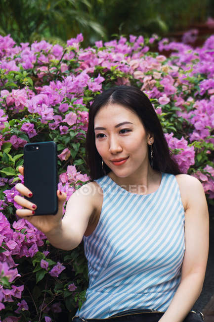 Young asian woman taking selfie with flowers — Stock Photo