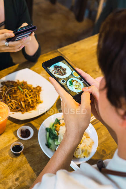 Young asian couple taking food photo in cafe — Stock Photo