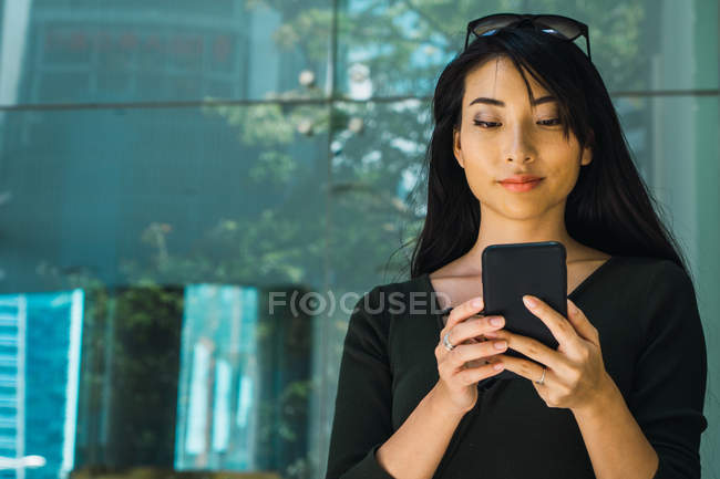 Retrato de joven mujer asiática usando smartphone - foto de stock