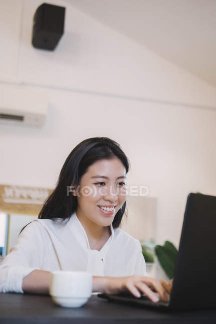 Young asian woman using laptop in creative modern office — Stock Photo