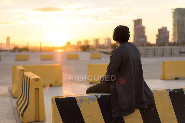 Vista trasera de la joven milenaria asiática disfrutando de la puesta de sol - foto de stock