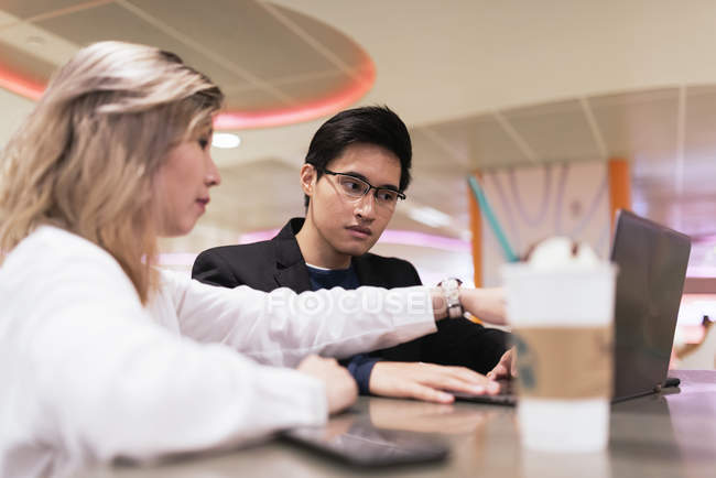 Junge asiatische Geschäftsleute mit Laptop und Drink im Flughafen — Stockfoto