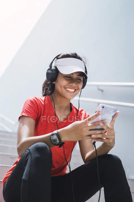 Young asian sporty woman using headphones and smart — Stock Photo