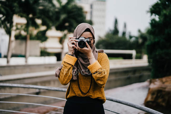 Young asian muslim woman in hijab taking photo with camera — Stock Photo