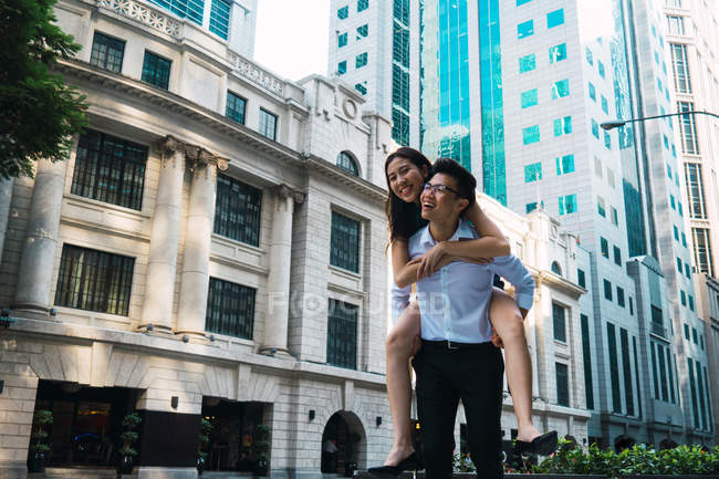 Jovem adulto casal de negócios, homem dando passeio de piggyback — Fotografia de Stock