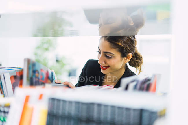 Young asian business woman looking at books in modern office — Stock Photo