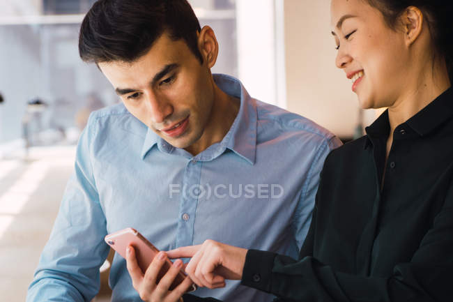 Young adult business people using smartphone at modern office — Stock Photo