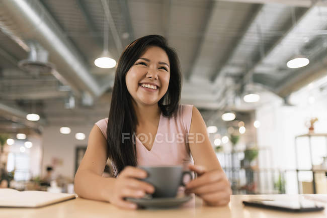 Jeune asiatique succès femme boire du café dans moderne bureau — Photo de stock
