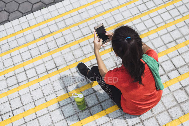 Молодая азиатская спортивная женщина с помощью смартфона — стоковое фото