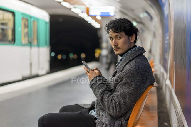 Young attractive casual asian using smartphone in subway — Stock Photo