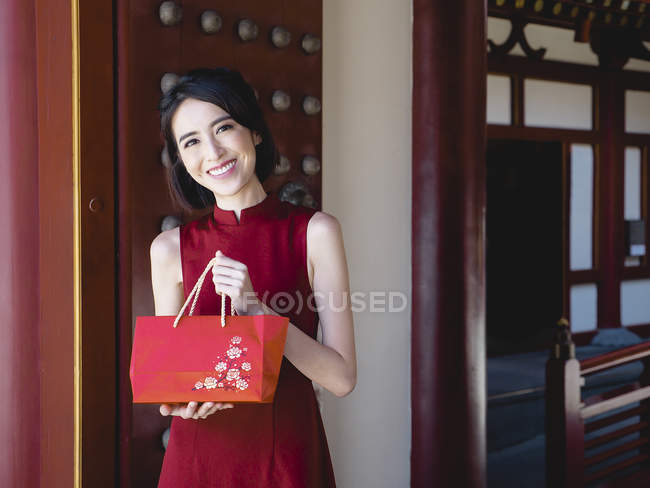 Mulher chinesa com bolsa vermelha olhando para a câmera — Fotografia de Stock