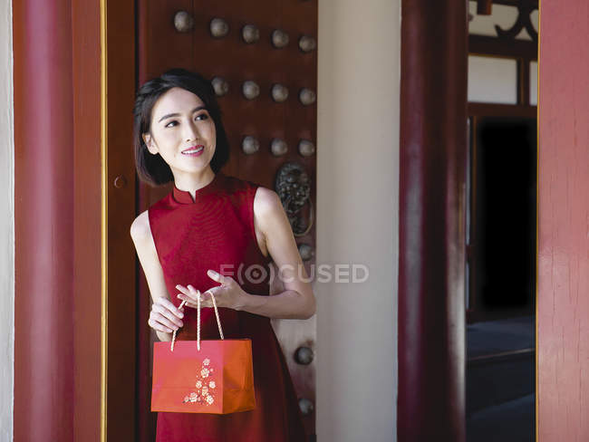 Chinese woman with red purse smilng outdoors — Stock Photo