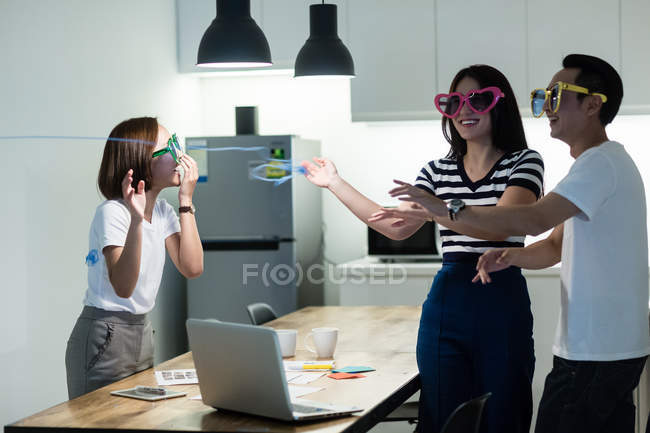 Young asian colleagues having fun with funny sunglasses in modern office — Stock Photo