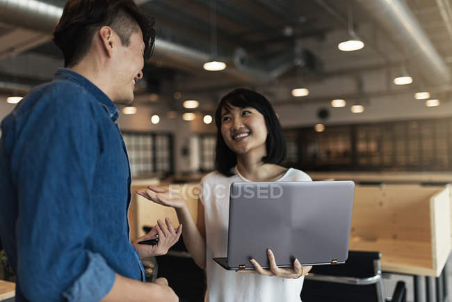 Deux jeunes asiatiques au travail avec ordinateur portable dans un bureau moderne — Photo de stock