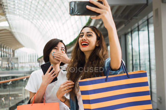 Молоді красиві азіатські жінки разом з сумками в магазині приймають селфі в міському місті — стокове фото