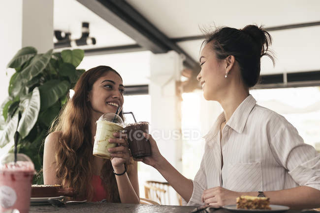 Две молодые красивые азиатские женщины проводят время в кафе — стоковое фото