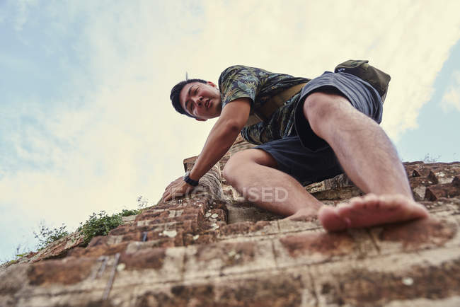 Молодой человек спускается по ступеням древнего храма Пятадар, Баган, Мьянма — стоковое фото