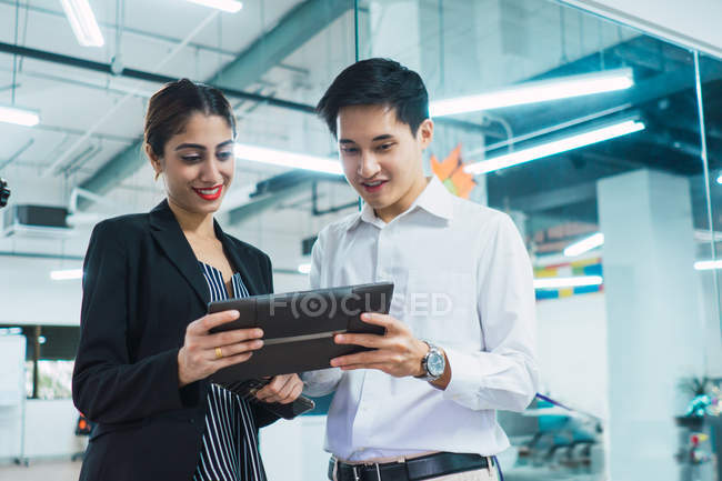 Молодые азиатские бизнесмены, использующие планшеты в современном офисе — стоковое фото