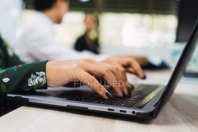 Cropped image of woman using laptop in office — Stock Photo