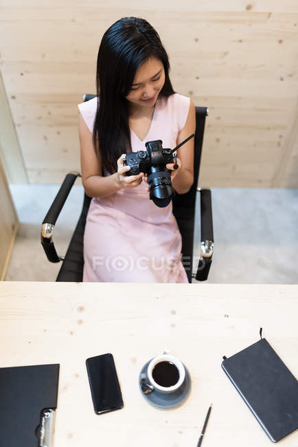 Junge erfolgreiche asiatische Geschäftsfrau hält Kamera in modernem Büro — Stockfoto