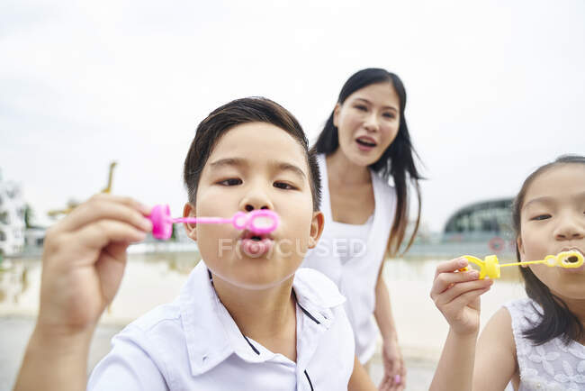 Happy asian family together, children making soap bubbles — Stock Photo