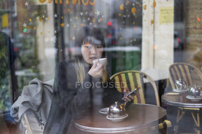 Young attractive casual asian woman drinking coffee in cafe — Stock Photo