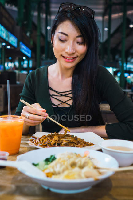 Jovem asiático mulher comer alimentos com pauzinhos — Fotografia de Stock