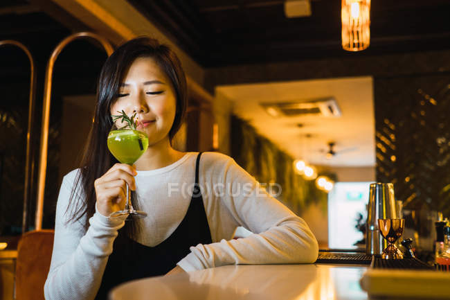 Young asian woman taking drink in comfortable bar — Stock Photo