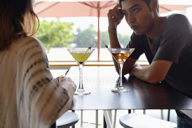 Young attractive asian couple having drink in cafe — Stock Photo