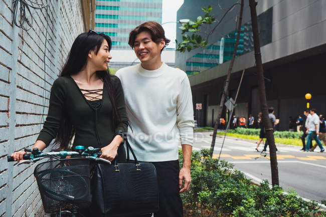 Joven asiático pareja caminando en calle con bicicleta - foto de stock