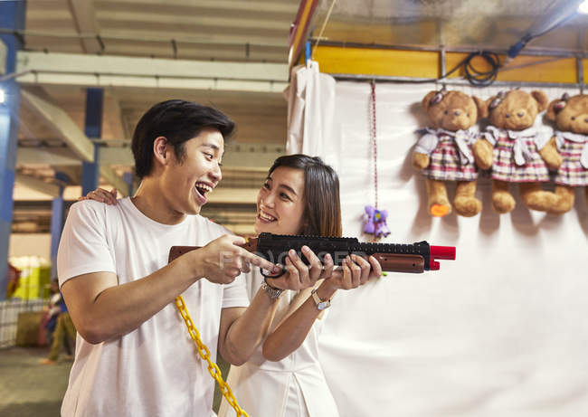 Couple jouant à un jeu de tir à un carnaval pour gagner des prix à Singapour — Photo de stock