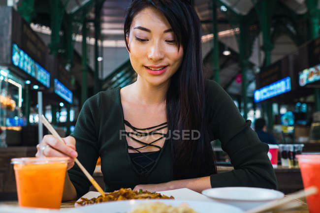 Jovem asiático mulher comer alimentos com pauzinhos — Fotografia de Stock